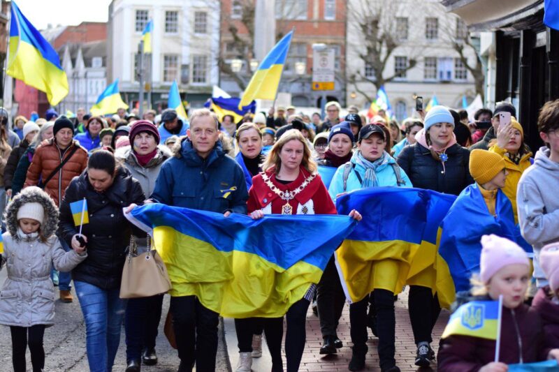 Members of a crowd holding the Ukrainian Flag in Reading town centre