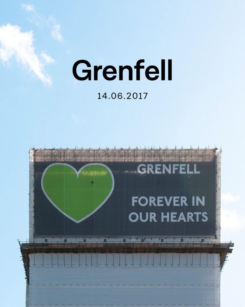 Photograph of Grenfell Tower covered in scaffolding with a sign reading 